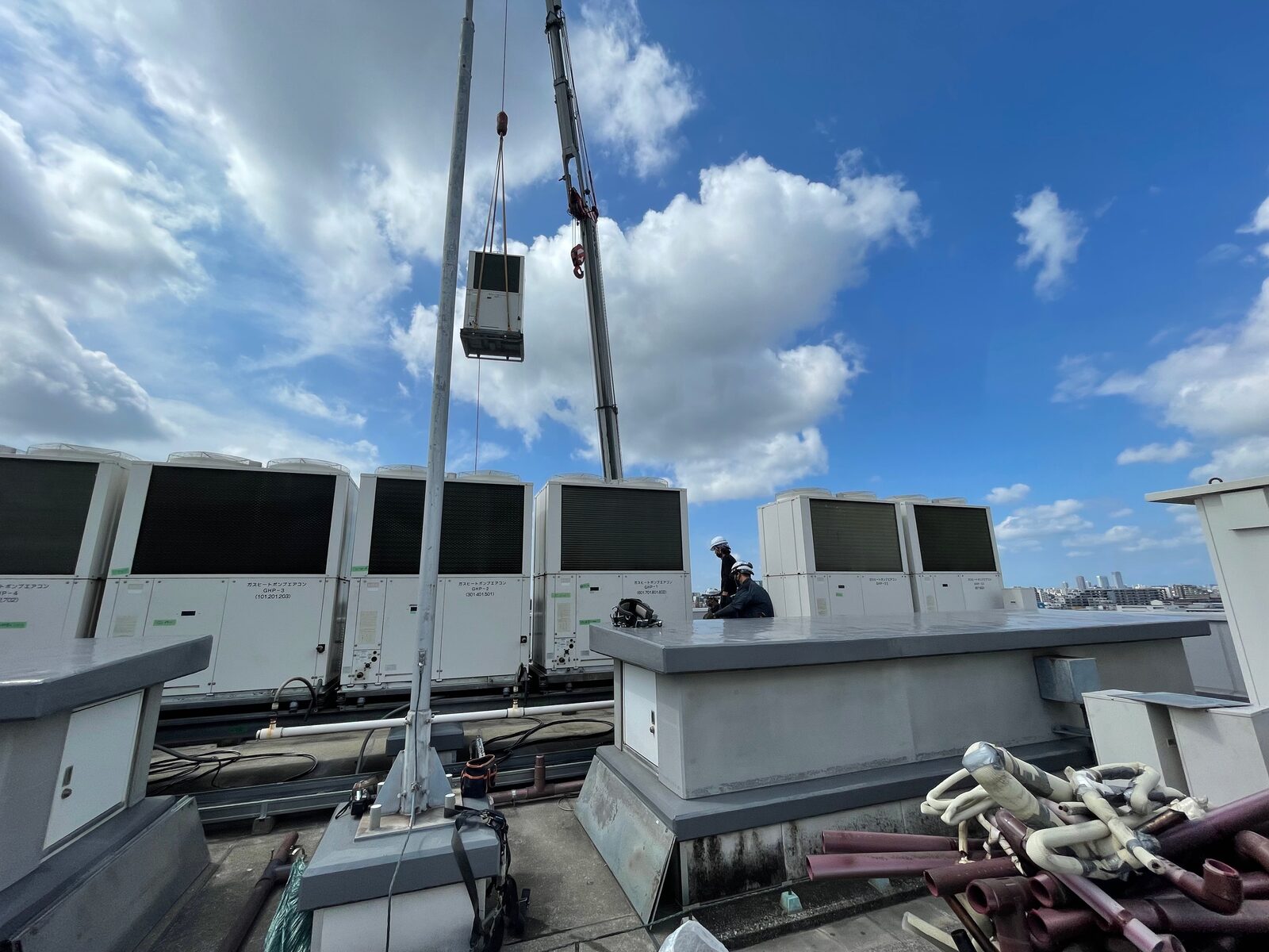 屋上へ空調室外機を吊り込むクレーン作業