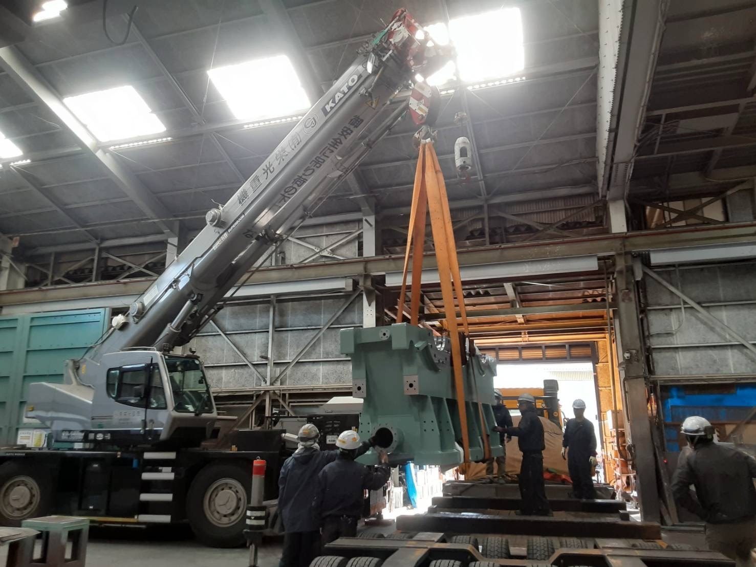 工場の建屋内で機械を吊り上げているクレーン