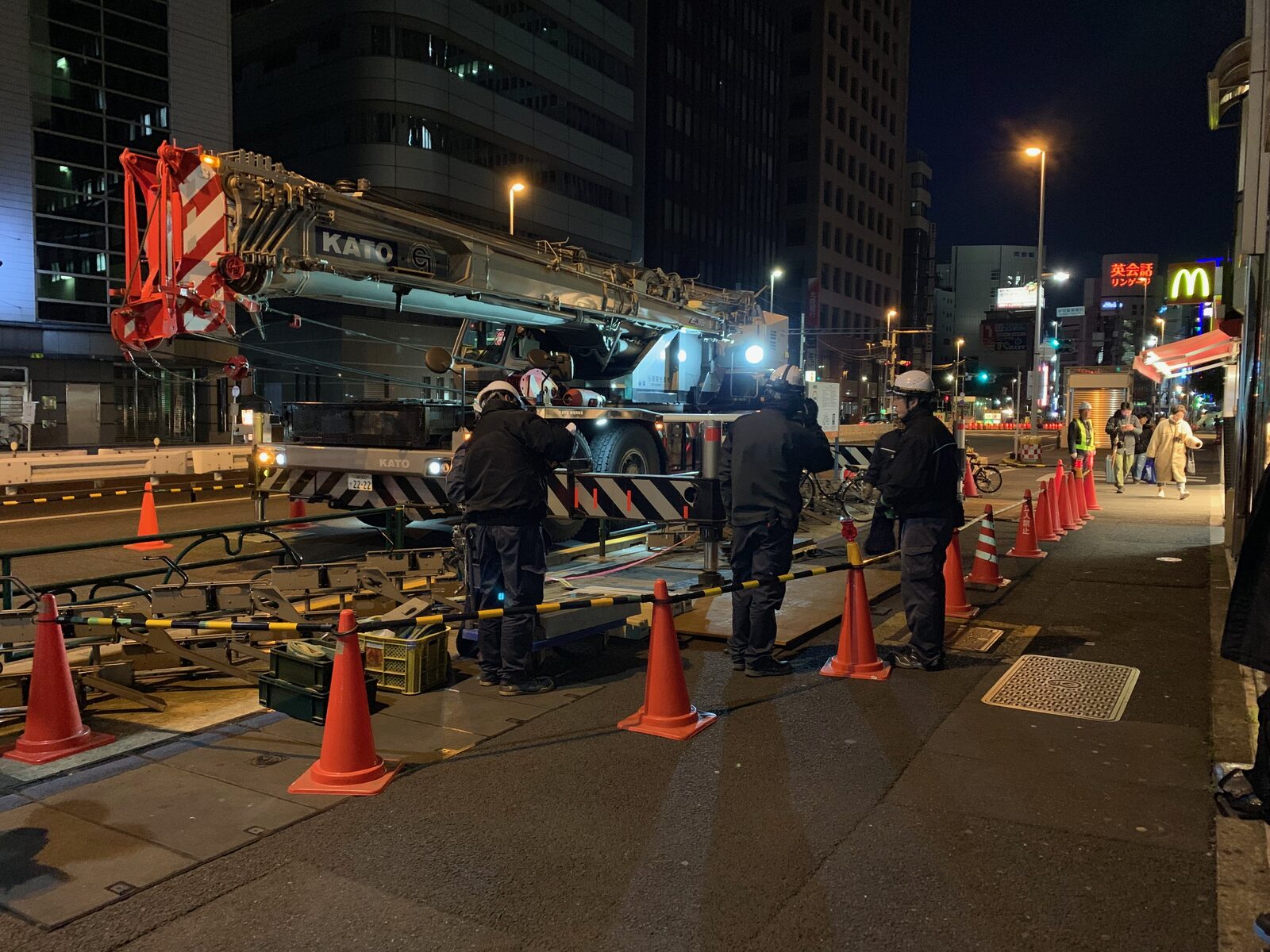 夜間の市街地で歩道を規制して行うクレーン作業