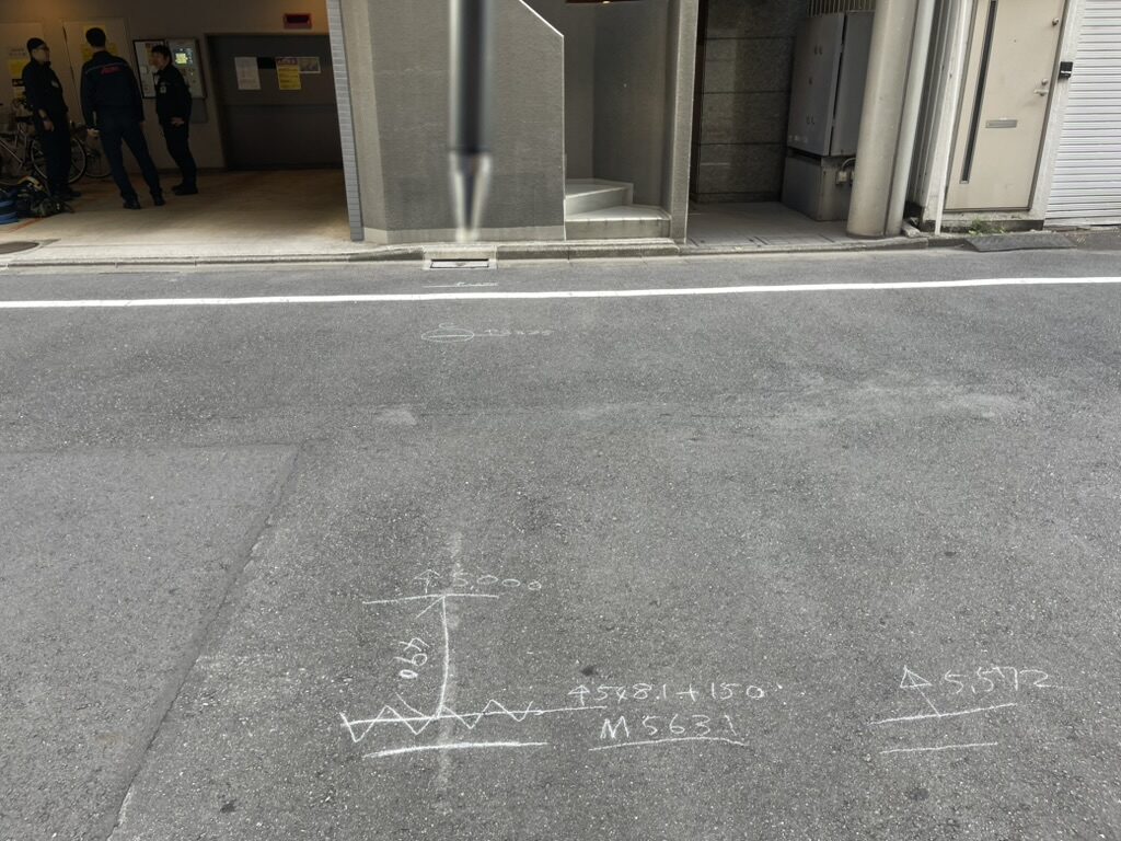路面にチョークで寸法と角度を書き込んだ現場調査の記録