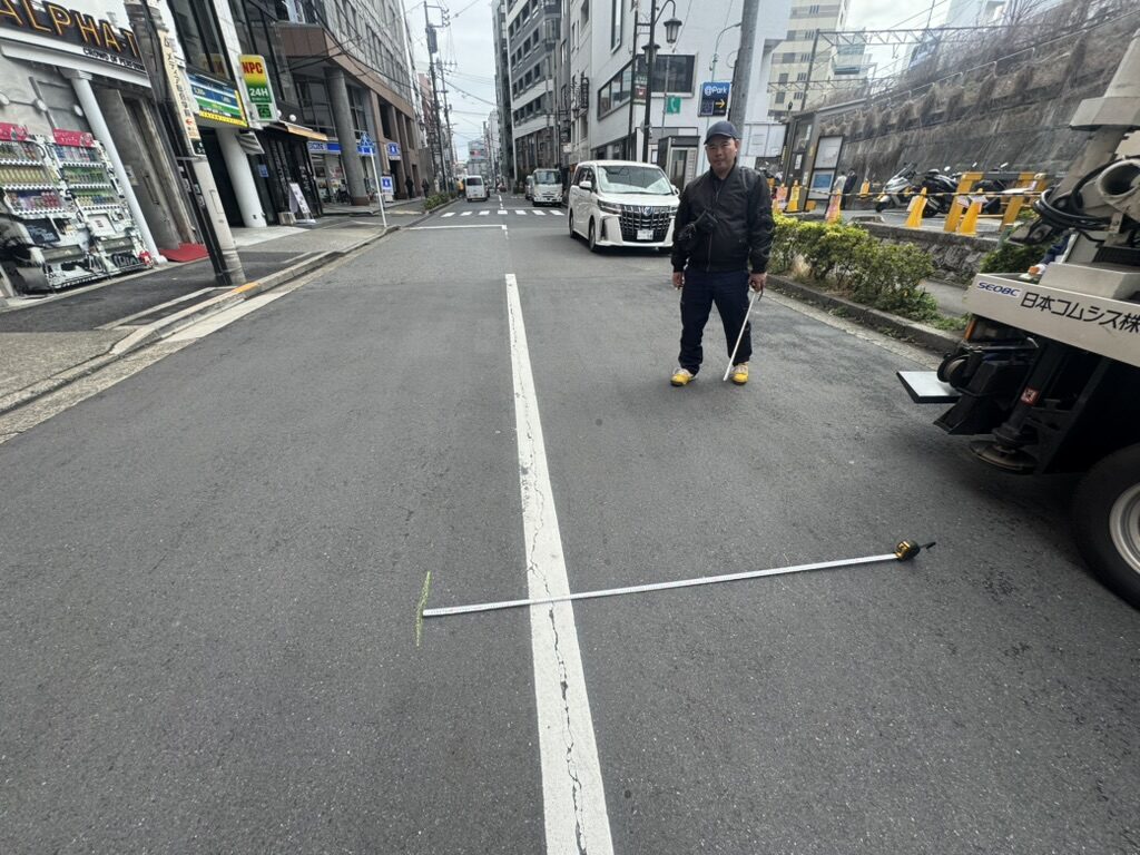 道路にメジャーを渡して幅員を測っている様子