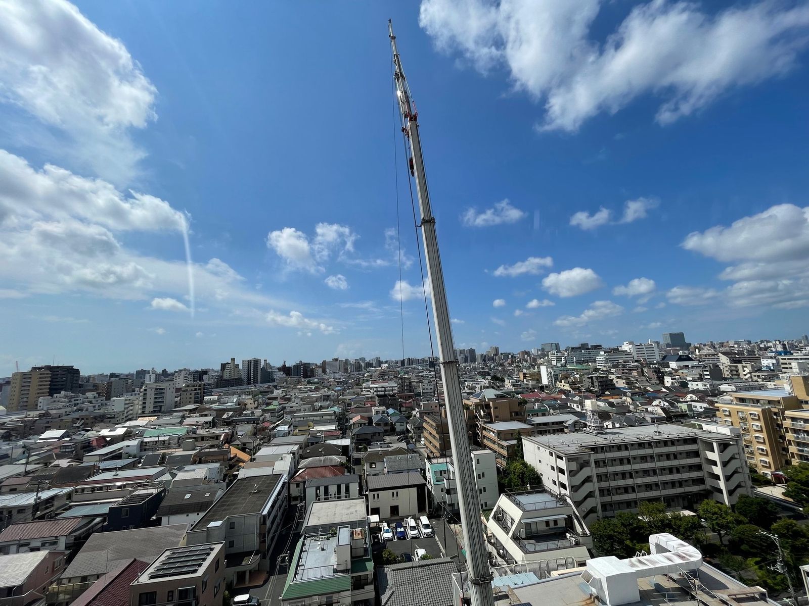 屋上の空調設備をクレーンで揚重する様子
